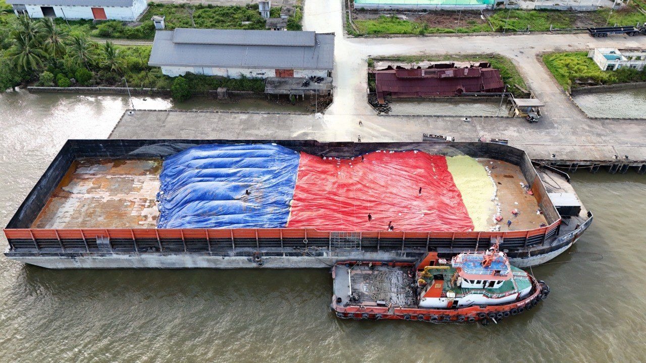 Tongkang bermuatan sulfur tertutup terpal, bersandar di dermaga dengan kapal tunda